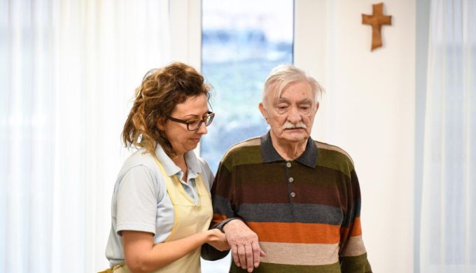 Pflegerin hilft Altenheimbewohner beim Gehen
